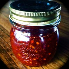 a glass jar filled with red liquid sitting on top of a wooden table