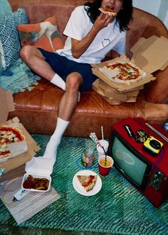 a woman sitting on a couch eating pizza