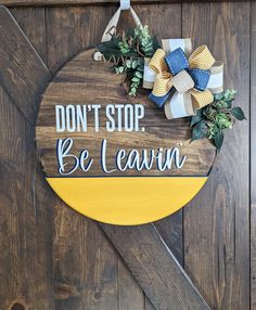 a wooden sign that says don't stop be leaven on it with a bow