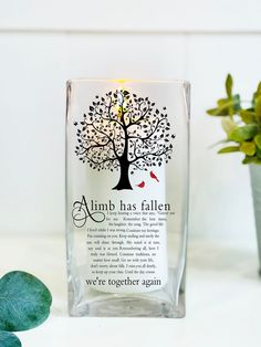 a glass vase with a tree on it and a lit candle in the middle that reads, almb has fallen we're together again again