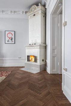 an empty room with a fireplace in the center and wood floors on both sides, white walls and parquet flooring