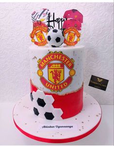 a birthday cake with soccer balls and manchester united crests on it's side