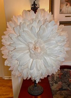 a large white flower sitting on top of a wooden table next to a framed photo