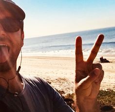 a man making the peace sign at the beach