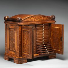 an antique wooden cabinet with intricate carvings on the front and sides, open doors at the top