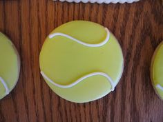 three decorated cookies with tennis balls on them sitting on a wooden table next to each other