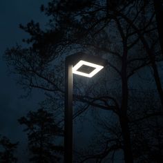 a street light in front of some trees at night