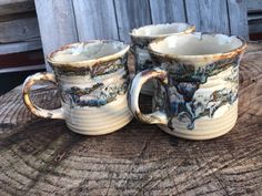 three coffee cups sitting on top of a wooden table