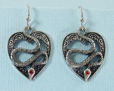 Make a statement with these silver snake earrings. They feature small pendants with a snake curled within a heart. The pendants are silver plate with darkening in the recessed areas to highlight the details. A tiny red rhinestone accents the eye. Earrings are 1 3/16 inches long with screw back and comfort cushion. See photos 3 - 4 for size reference. Matching necklace - https://www.etsy.com/listing/1281509919/goth-snake-necklace-reptile-snake-lovers ---------------------------------- Thank you f Silver Snake-shaped Oxidized Jewelry, Silver Oxidized Snake-shaped Jewelry, Silver Metal Dangle Heart Earrings, Oxidized Silver Snake Jewelry, Nickel-free Silver Metal Heart Earrings, Silver Metal Heart Earrings For Anniversary, Symbolic Heart-shaped Metal Jewelry, Silver Heart-shaped Pierced Jewelry, Silver Snake-shaped Metal Earrings