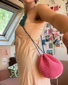 a woman holding a pink crocheted purse