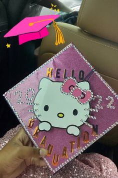 someone holding up a hello kitty graduation cap