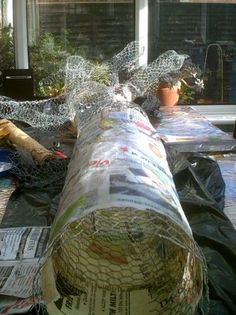 there is a roll of newspaper on the ground next to a planter and window