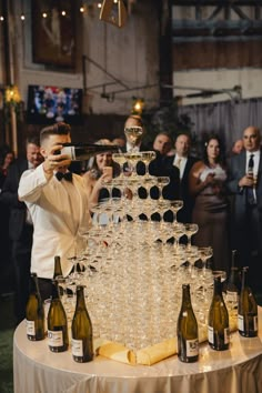 a man standing in front of a table filled with wine glasses and champagne bottles,