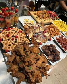 many different types of food are on the buffet table, including waffles and fruit