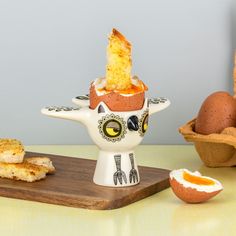 an egg cup with some kind of weird thing in it next to eggs on a cutting board