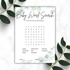 the baby word search game is next to some green leaves on a white marble surface