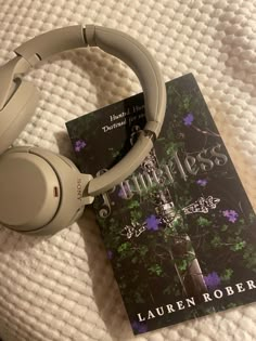 a book and headphones sitting on top of a bed