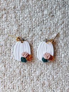 two earrings with flowers on them sitting on a carpet