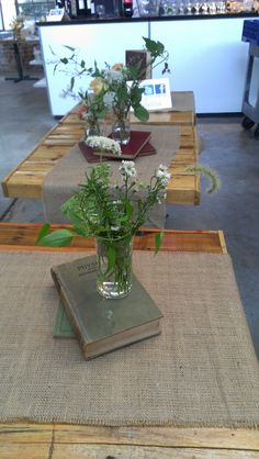 flowers in a vase sitting on top of a table with a book next to it