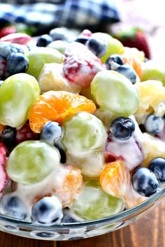 a glass bowl filled with fruit salad on top of a wooden table