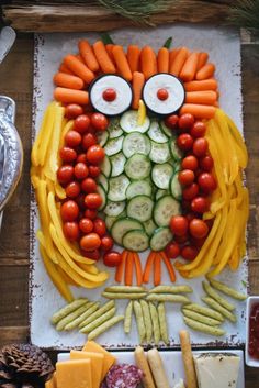 an owl made out of veggies and meats on a table with pine cones