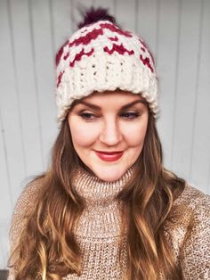 a woman wearing a white and red knitted hat with pom - pom