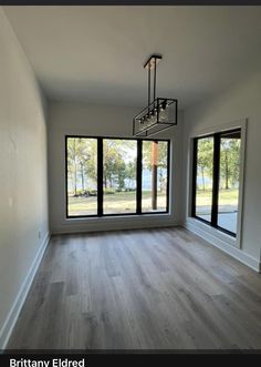 an empty room with large windows and wooden floors