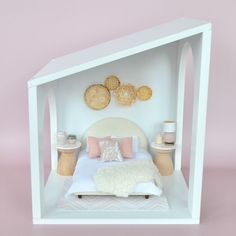 a white dollhouse bed with pillows and blankets