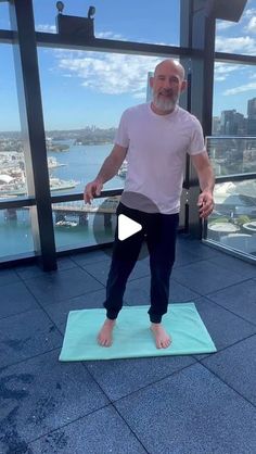 a man standing on top of a yoga mat in front of a cityscape