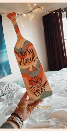 someone holding up a wine bottle that says baby mardi gras on the bed