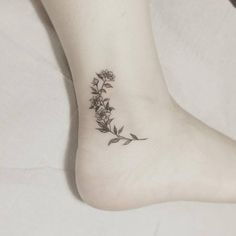 a small flower tattoo on the ankle is shown in black and grey ink, with an arrow