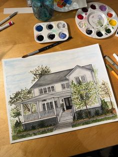 a drawing of a house on a table with watercolor paints