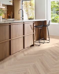 a kitchen with wooden floors and cabinets in the background, there is a bar stool next to the counter