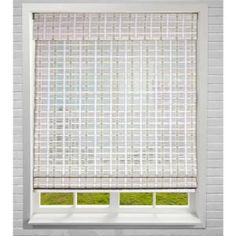 a white brick wall with a window covered in green grass and the blinds are closed