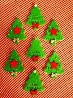 christmas cookies decorated with green and red icing are arranged on a checkered tablecloth