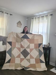 a woman is holding up a quilt in her living room