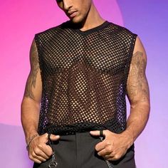 a man with tattoos on his arm and chest wearing a black mesh shirt over a gray suit