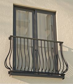 a balcony with wrought iron railings and glass doors on the side of a building