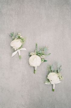 three bridals with white flowers and greenery are arranged on a gray surface