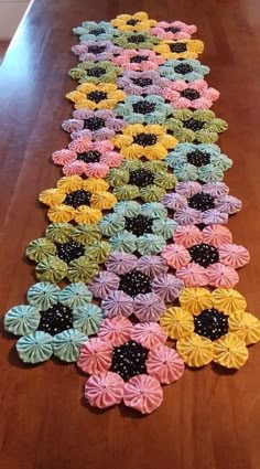 a wooden table topped with lots of different colored paper flowers on top of each other