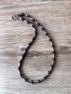 A medium weight beaded mens necklace made with gray hematite and shiny onyx black beads. - Length is 23" long (more lengths are listed) - Gunmetal toggle clasp - more styles are listed- 8mm diameter beads- Flexible nylon coated stainless steel beading wire The mannequin's neck size is 14.5". Here is a matching bracelet. https://www.danaleblanc.com/collections/mens-bracelet/products/black-onyx-gray-hematite-bead-stone-bracelet-jewelry-jayce Please remove jewelry before swimming or showering. We u Artisan Black Adjustable Beaded Necklace, Silver Hematite Beaded Necklace With Black Beads, Black Long Metal Beaded Necklace, Adjustable Hematite Necklace With Black Beads, Silver Hematite Gemstone Beaded Necklace, Pearl Statement Necklace, Long Beaded Necklace, Beaded Statement Necklace, Gold Gift