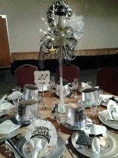 the table is set with silver and white dishes, napkins, and place settings