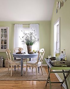 an image of a dining room with green walls and white curtains on the windowsill