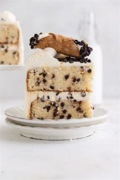 a slice of cake on a plate with chocolate chips and cream frosting, next to a bottle of milk