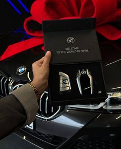 the man is holding his new bmw car keys in its gift box and it says welcome to the world of bmw