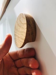 a hand holding a wooden object on the wall