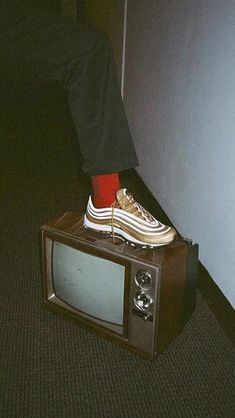 a person sitting on top of a tv with their feet propped up against the wall