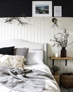 a white bed with pillows and blankets on top of it next to a night stand