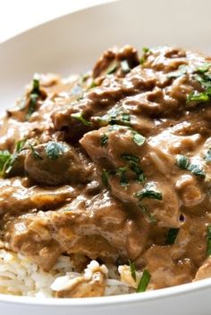 a white plate topped with rice and meat covered in gravy