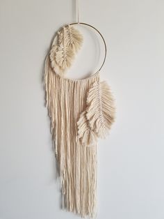 a white wall hanging with some tassels attached to it's sides and a circular ring around the edge